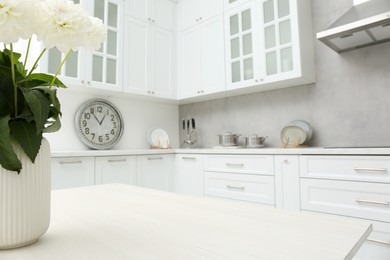 Photo of Bouquet of flowers on stylish white wooden table in kitchen, space for text. Interior design