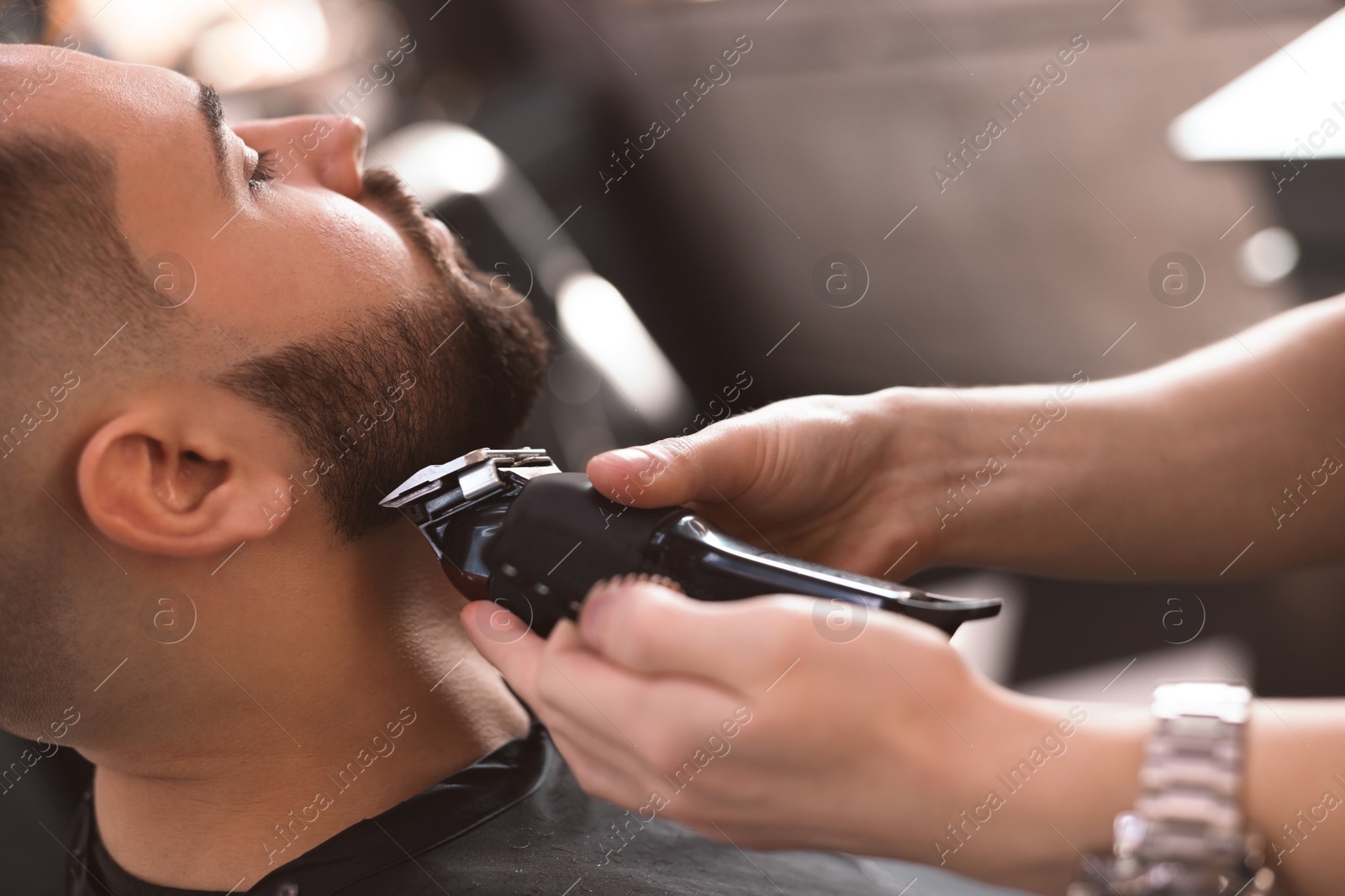 Photo of Professional hairdresser working with client in barbershop