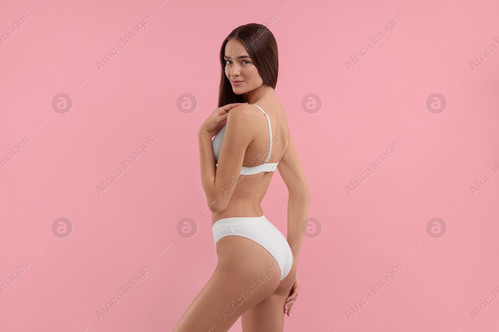 Photo of Young woman in stylish white bikini on pink background