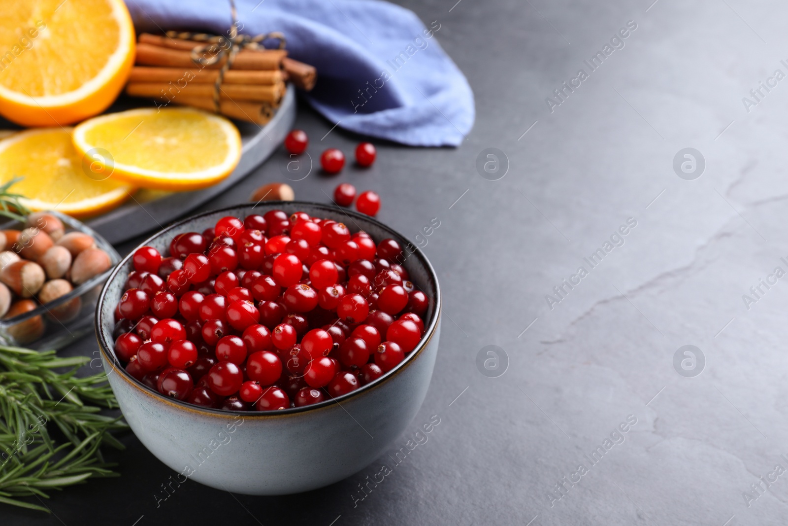 Photo of Fresh ripe cranberries and spices on grey table. Space for text