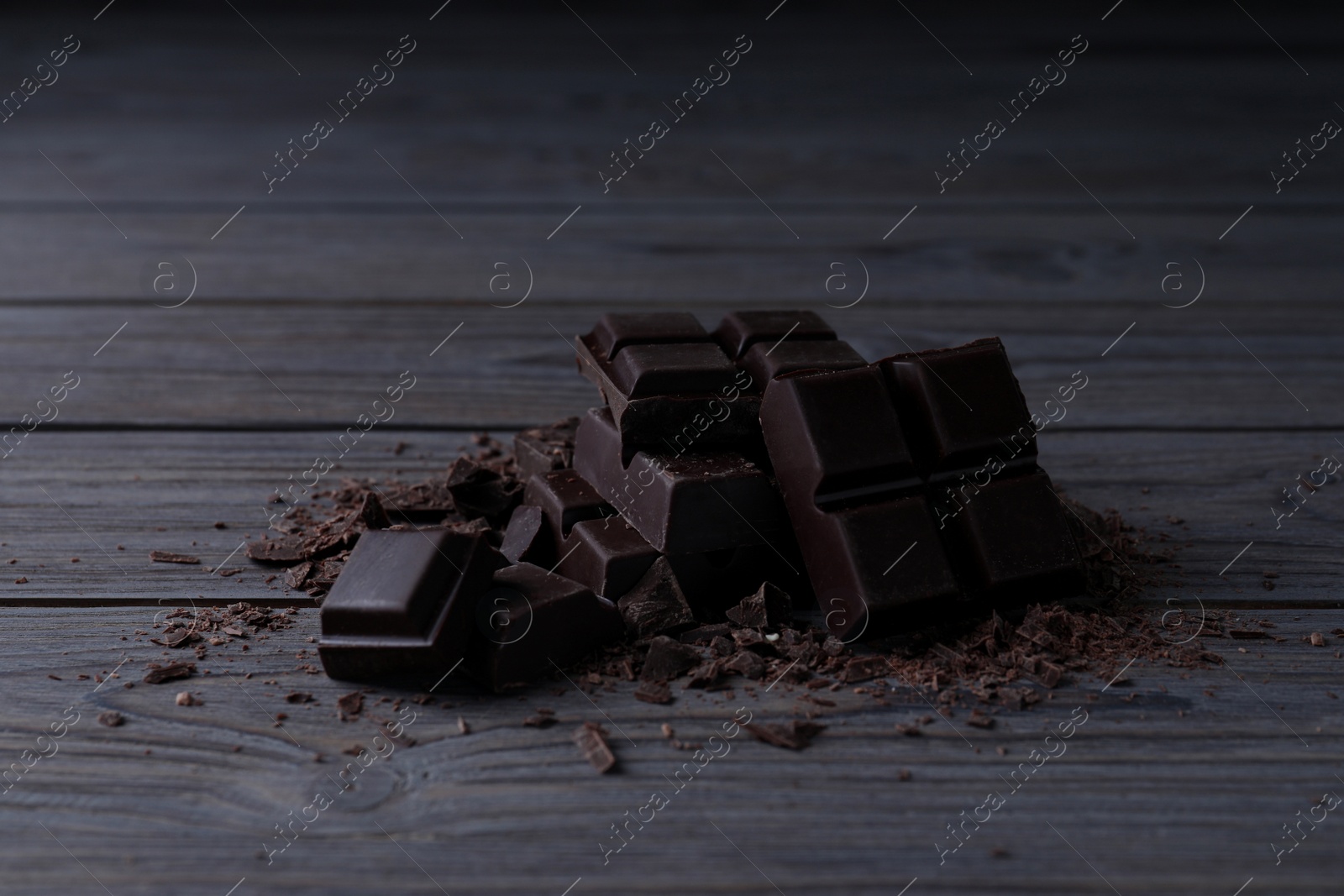 Photo of Pieces of delicious dark chocolate on wooden table