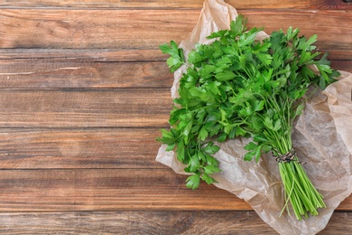 Photo of Fresh green parsley and space for text on wooden background, top view