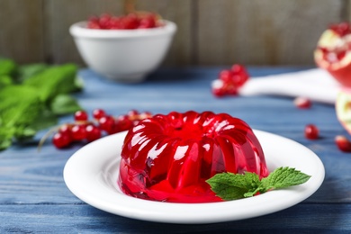 Delicious fresh red jelly with mint on blue wooden table