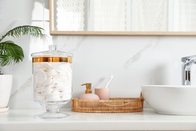 Photo of Jar with cotton pads on bathroom countertop