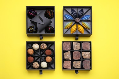 Photo of Boxes of tasty chocolate candies on yellow background, flat lay