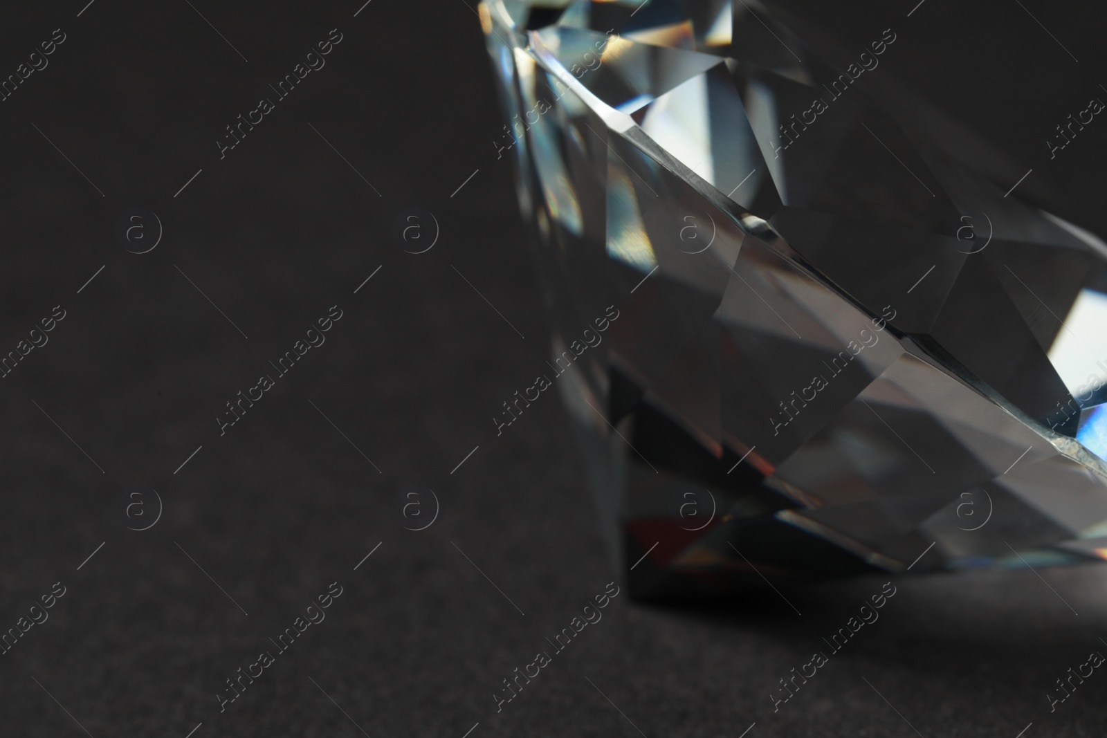 Photo of Beautiful dazzling diamond on dark background, closeup. Space for text