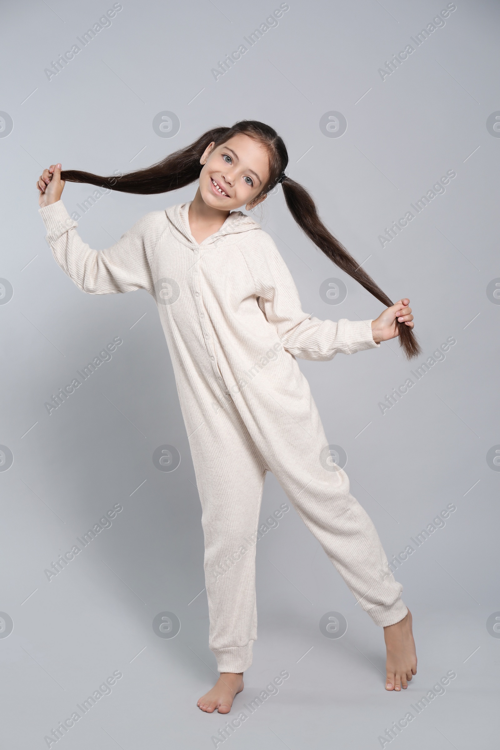 Photo of Cute girl in white pajamas on light grey background