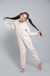 Photo of Cute girl in white pajamas on light grey background