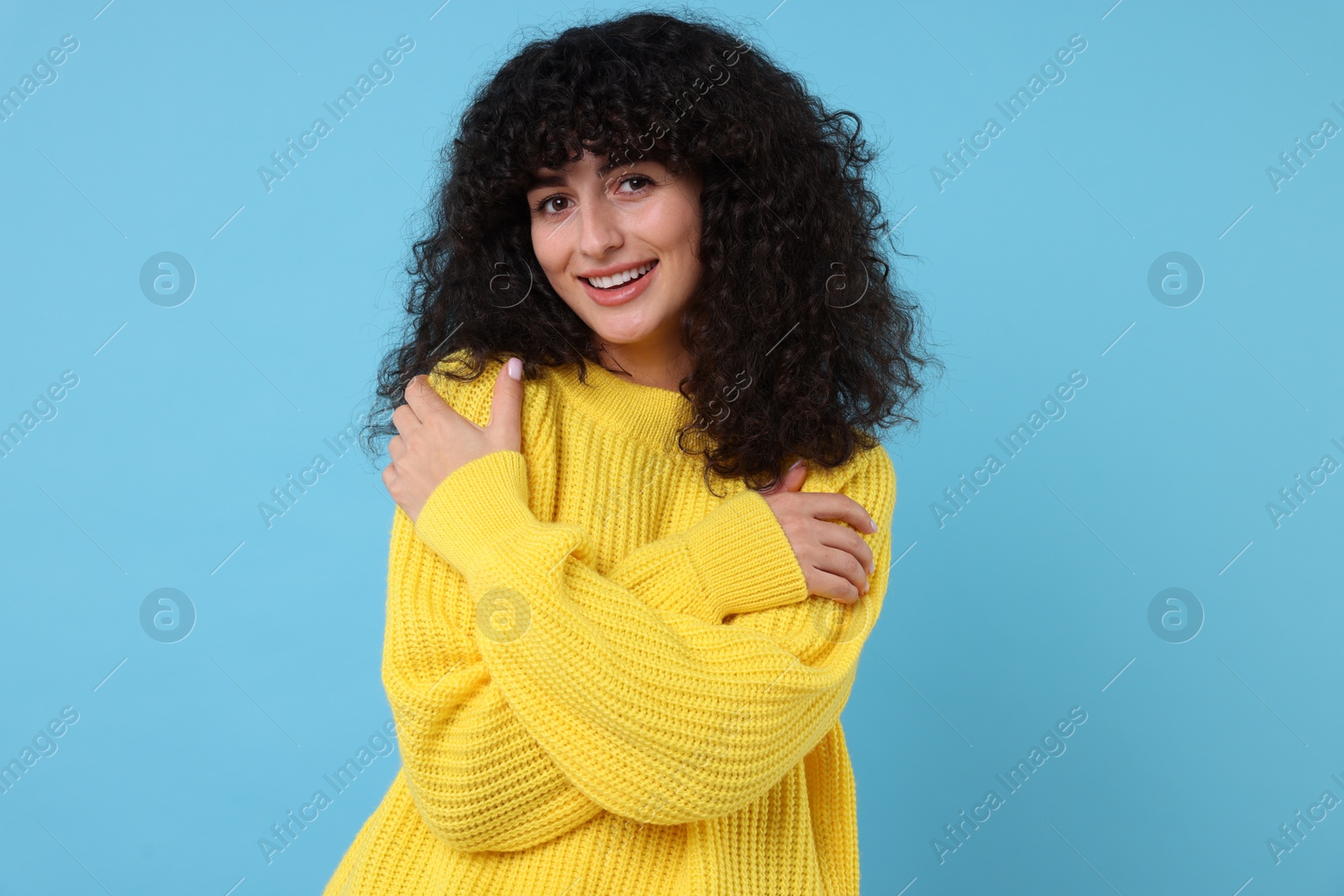 Photo of Happy young woman in stylish yellow sweater on light blue background