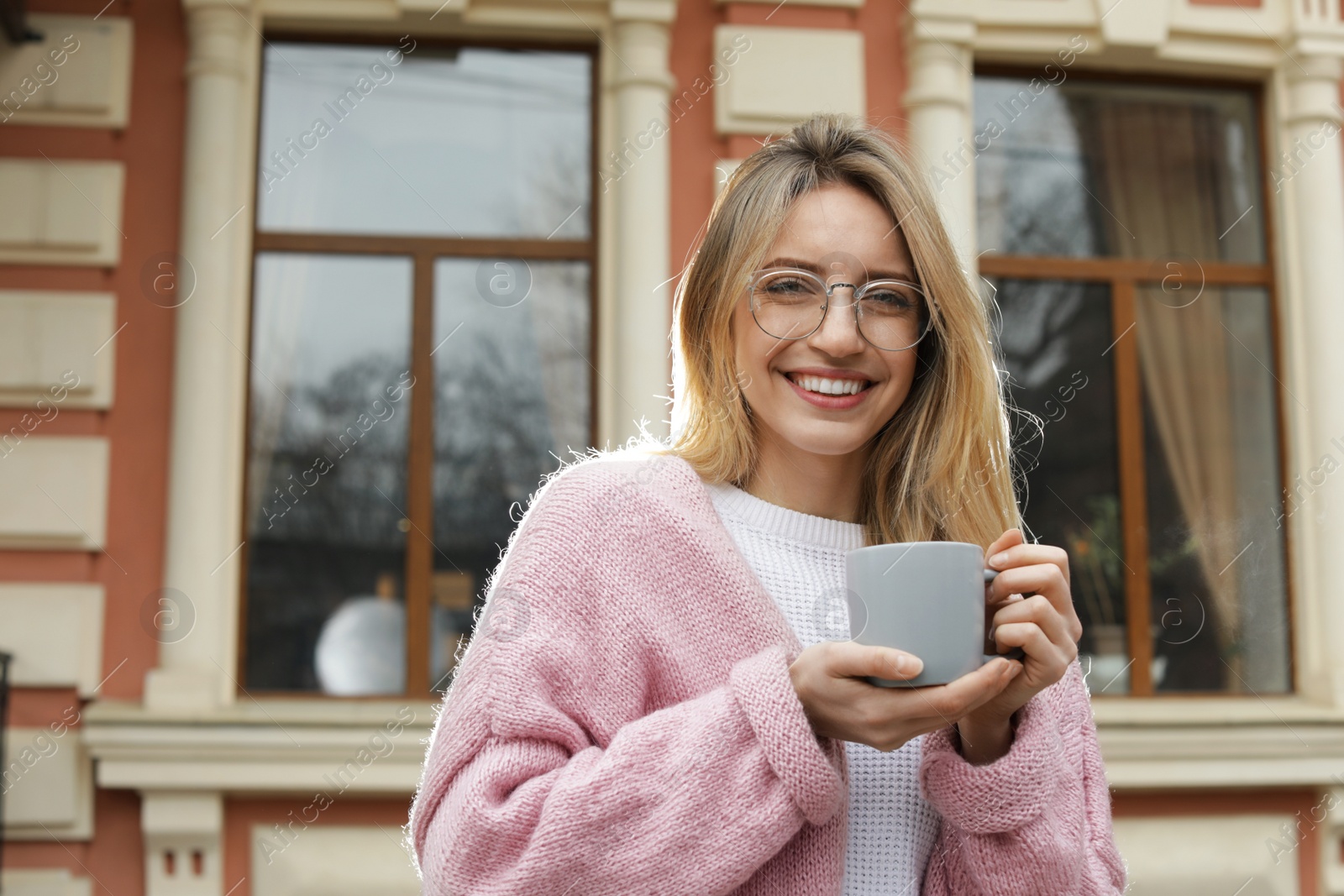 Photo of Young woman with cup of hot drink outdoors