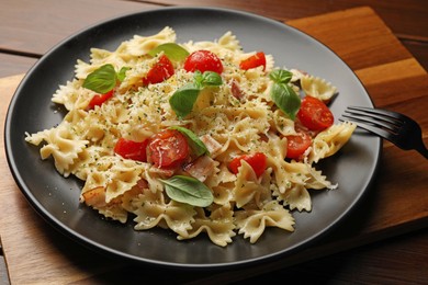Delicious pasta with tomatoes, basil and parmesan cheese on wooden table, closeup