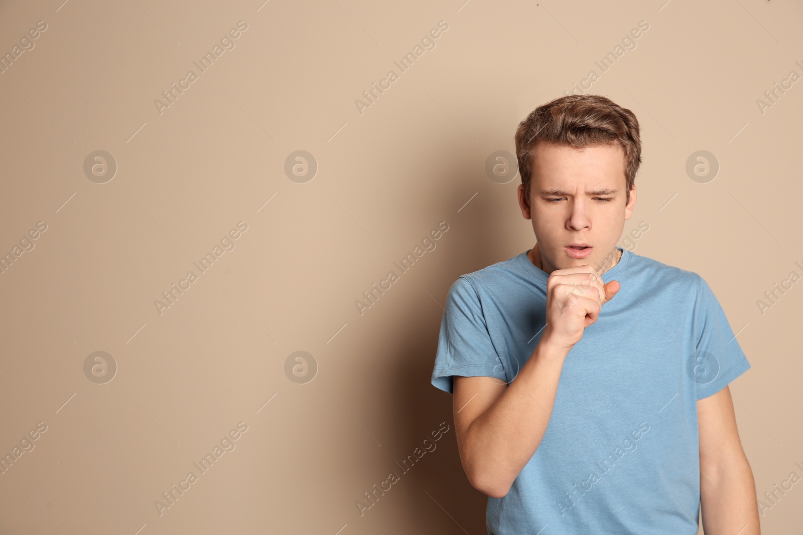 Photo of Teenage boy suffering from cough on color background. Space for text