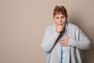 Elderly woman coughing against color background. Space for text