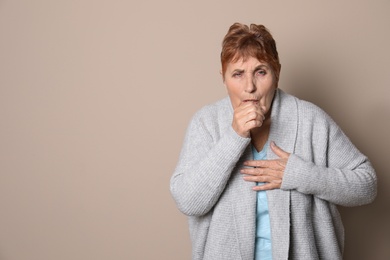 Photo of Elderly woman coughing against color background. Space for text