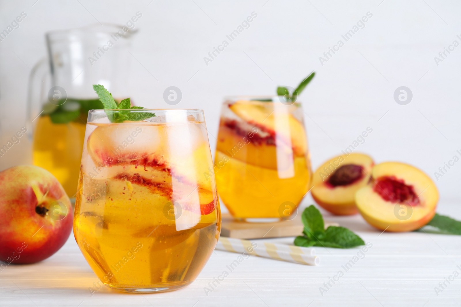 Photo of Delicious peach lemonade made with soda water and ingredients on white wooden table. Space for text