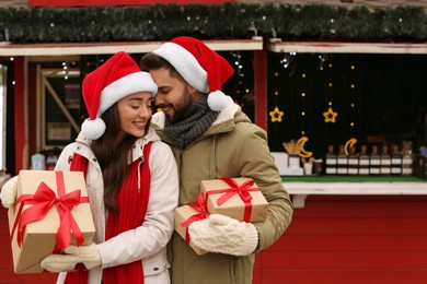 Photo of Lovely couple with Christmas presents at winter fair