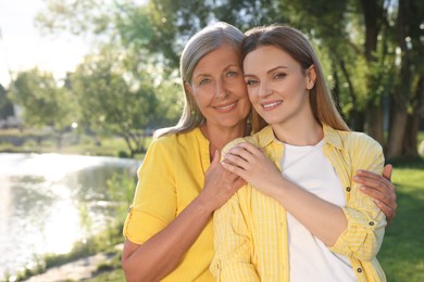 Photo of Family portrait of happy mother and daughter spending time together in park on sunny day. Space for text