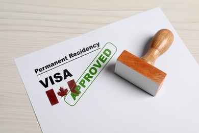 Image of Document with approved permanent residency visa in Canada and stamp on white wooden table