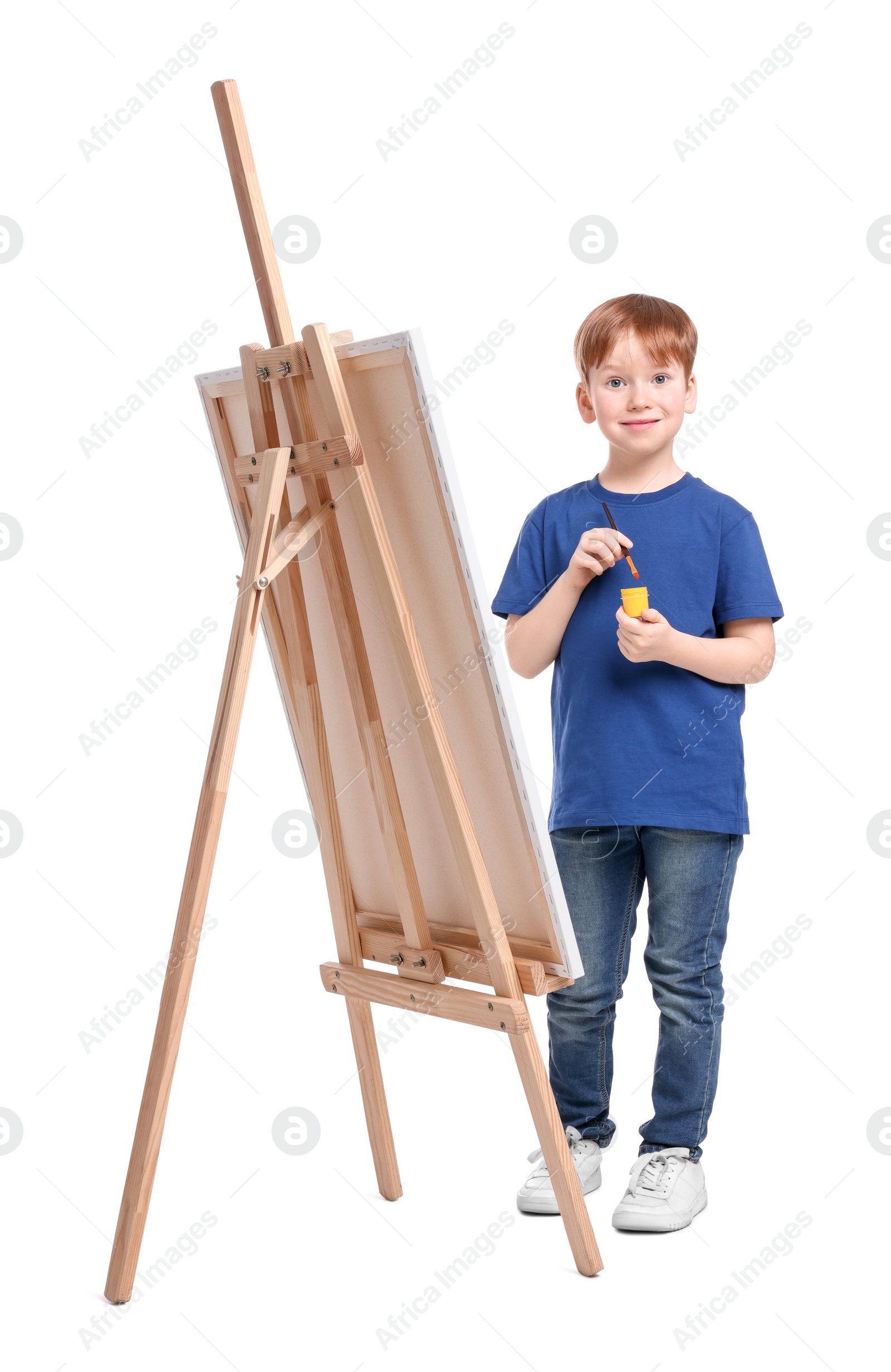 Photo of Little boy with brush near easel with canvas on white background. Creative hobby