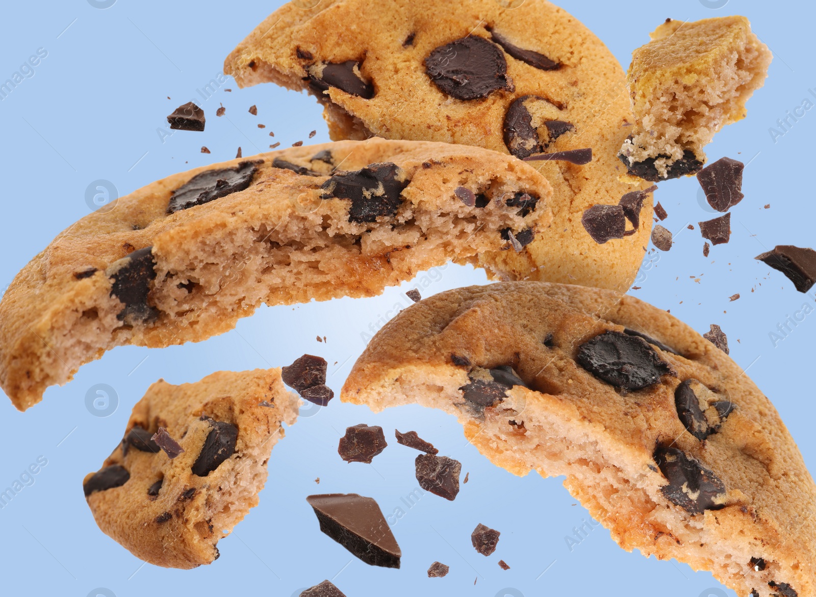 Image of Tasty chocolate chip cookies falling on light blue background