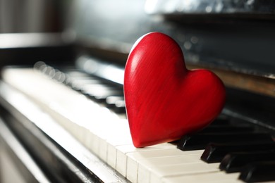 Photo of Red decorative heart on piano keys, closeup. Space for text
