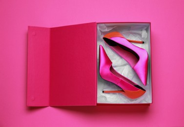Stylish women's shoes in cardboard box on pink background, top view