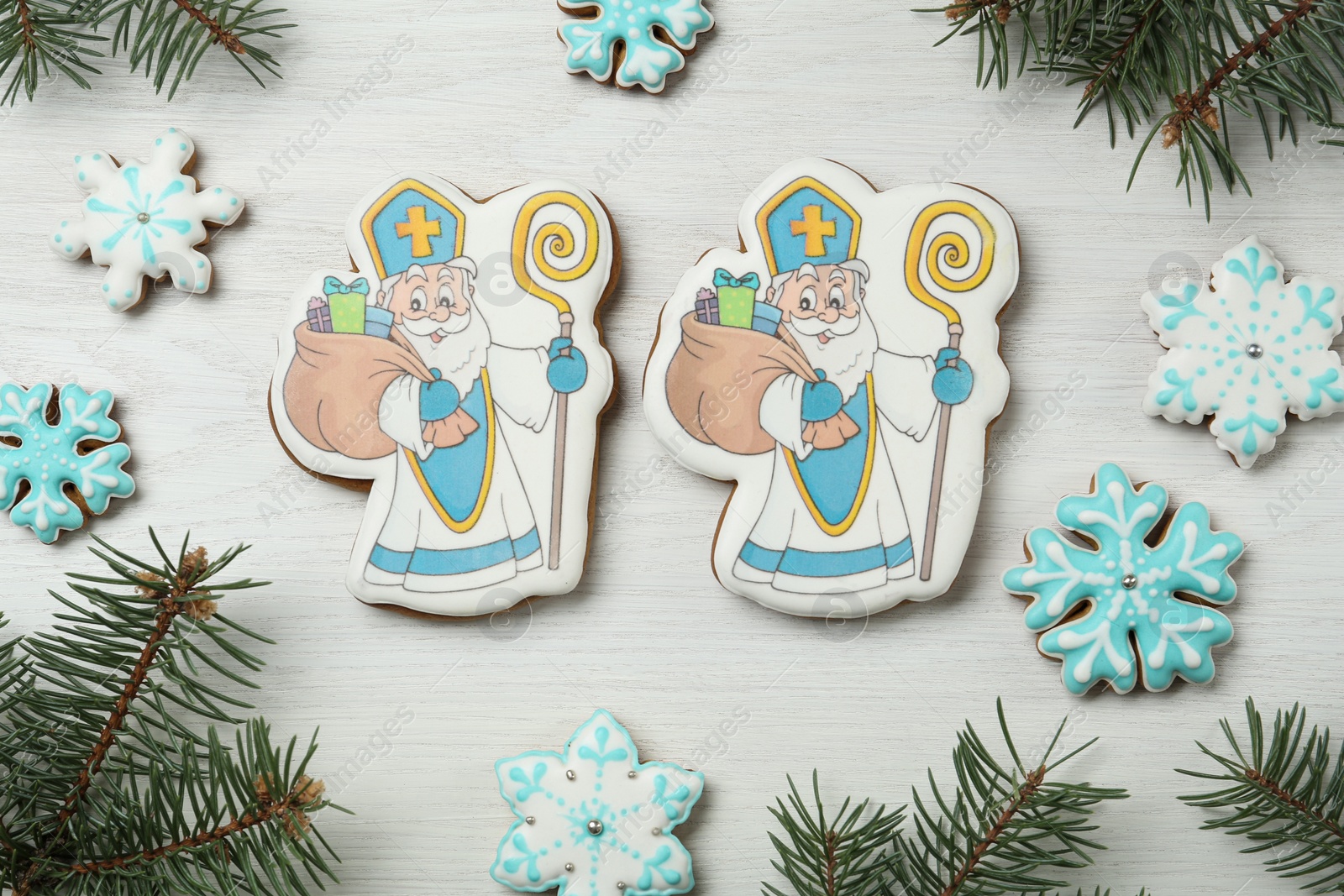 Photo of Delicious gingerbread cookies on white wooden table, flat lay. St. Nicholas Day celebration