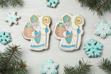 Delicious gingerbread cookies on white wooden table, flat lay. St. Nicholas Day celebration