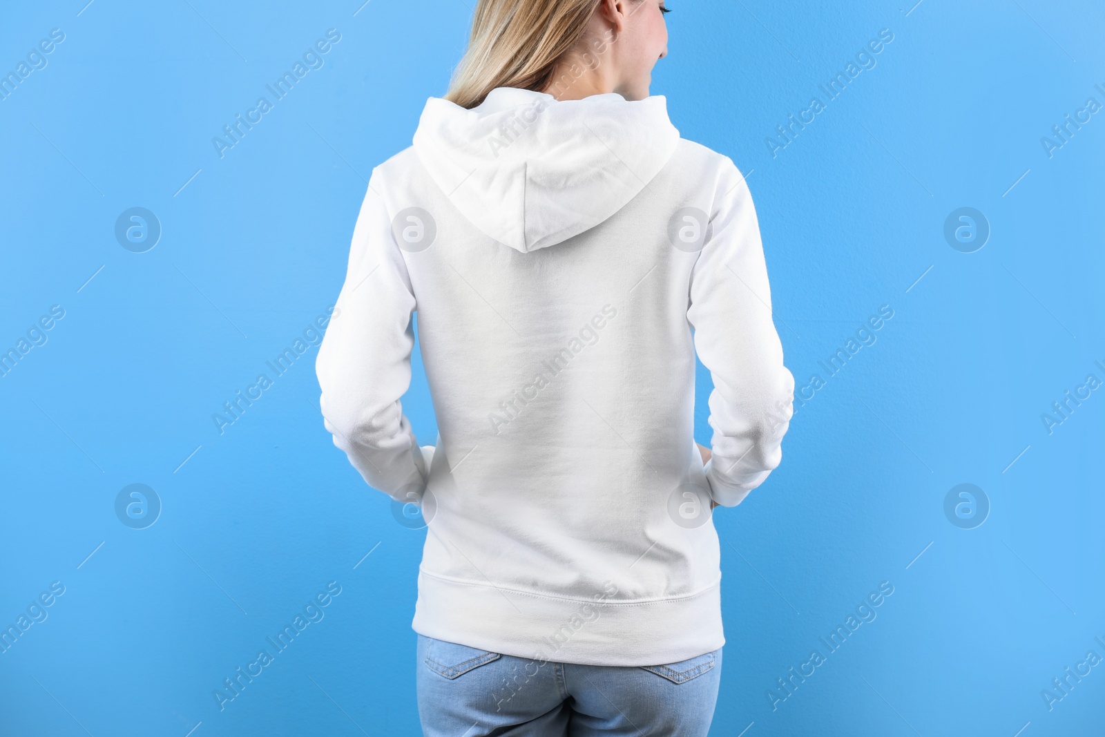 Photo of Woman in hoodie sweater on color background. Space for design