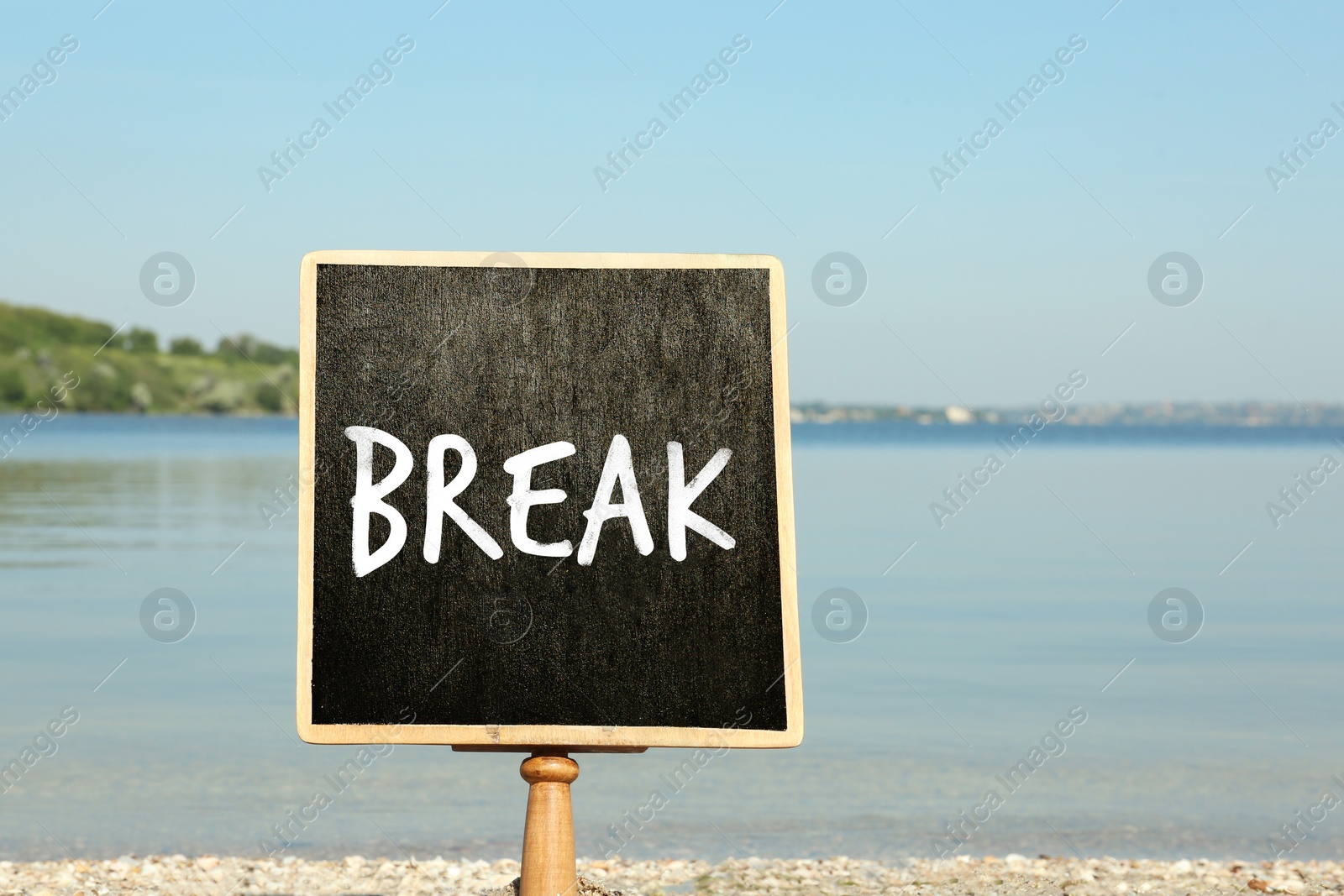 Image of Small black chalkboard with word Break on beach. School holidays 