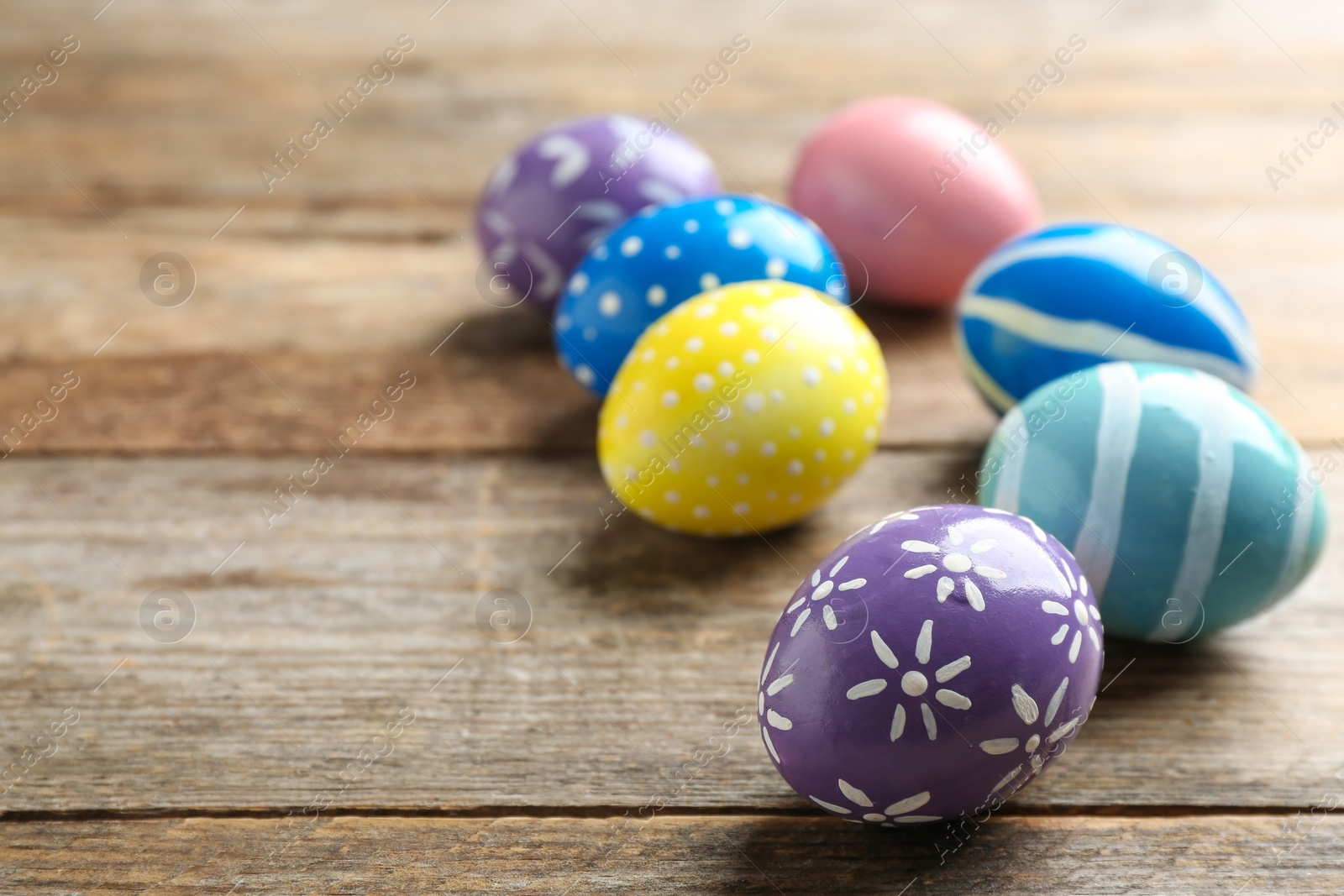 Photo of Painted Easter eggs on wooden table, space for text