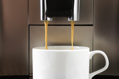 Photo of Modern espresso machine pouring coffee into cup, closeup