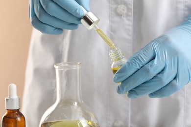 Photo of Developing cosmetic oil. Scientist with dropper and glass bottle, closeup