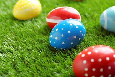 Colorful painted Easter eggs on green grass, space for text