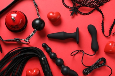 Different sex toys on red background, flat lay