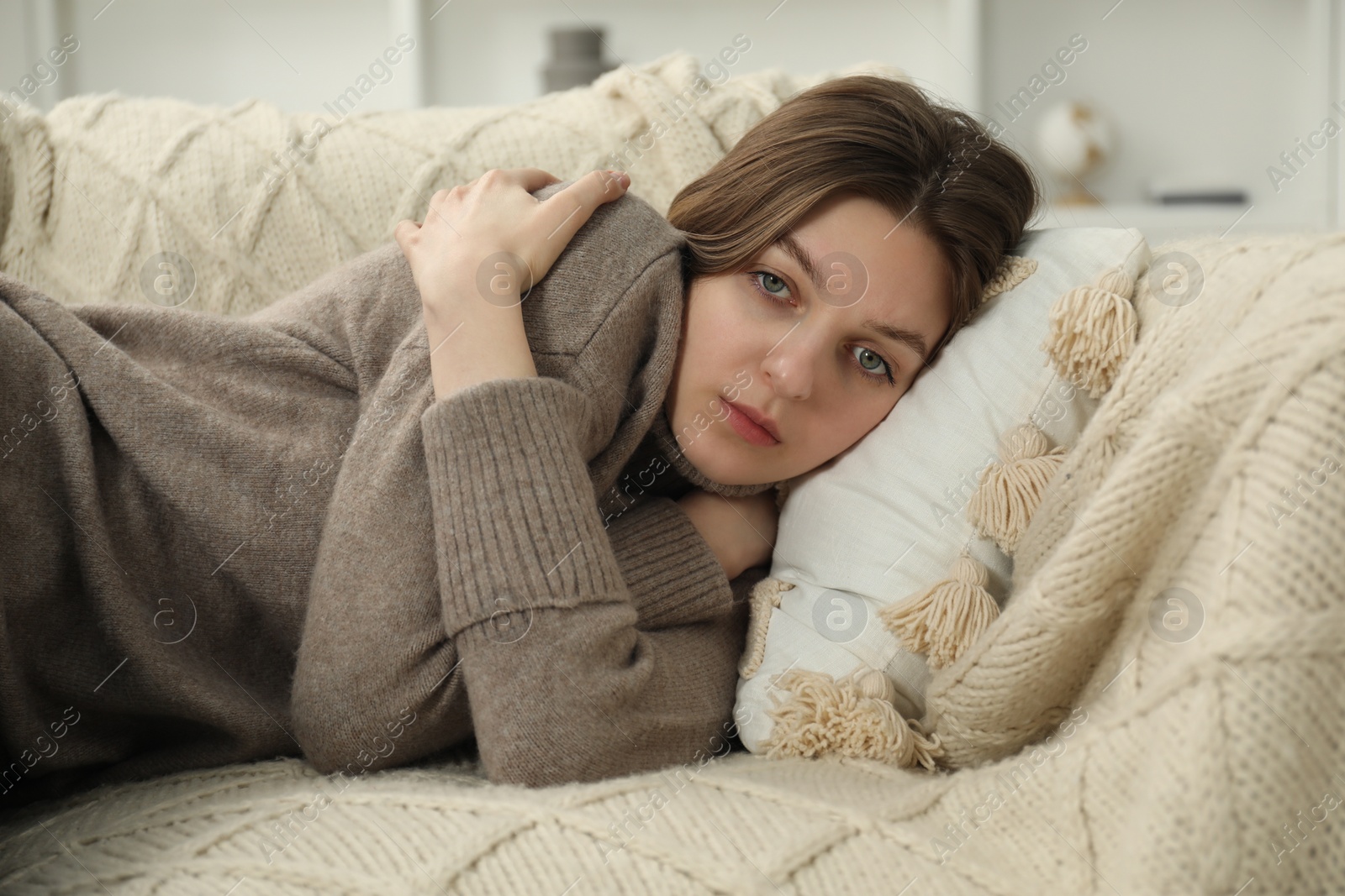 Photo of Sad young woman lying on sofa at home