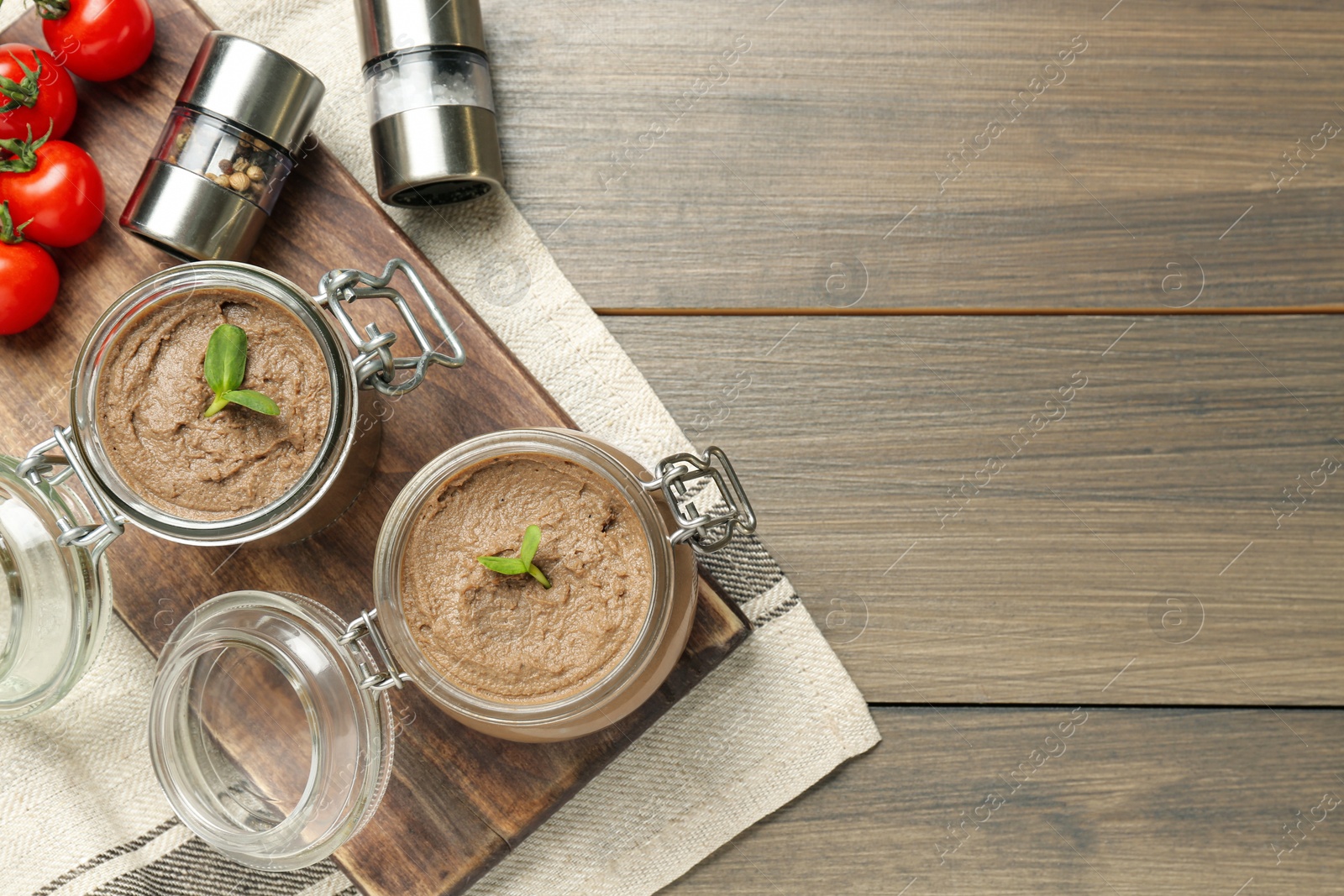 Photo of Glass jars with delicious liver pate on wooden table, top view. Space for text