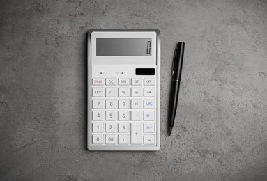 Calculator and pen on grey table, flat lay