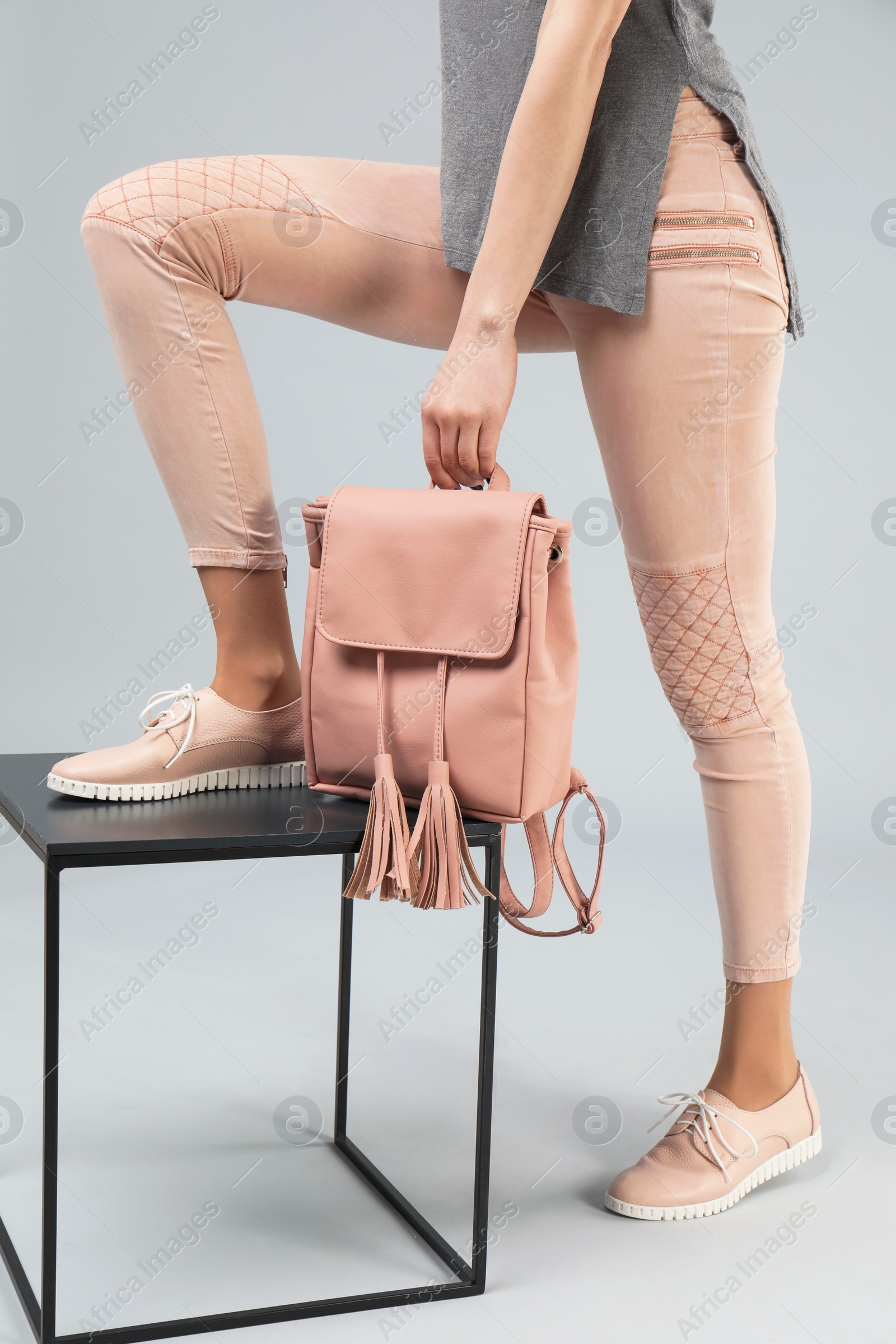 Photo of Woman in shoes with stylish backpack and stand on grey background, closeup