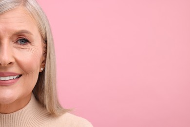 Photo of Portrait of beautiful middle aged woman on pink background, closeup. Space for text