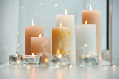 Beautiful burning candles and fairy lights on windowsill indoors