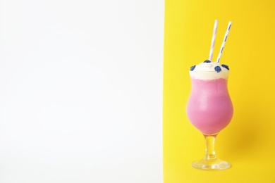 Glass of tasty milk shake and space for text on color background