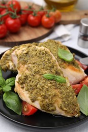 Photo of Delicious chicken breasts with pesto sauce, tomatoes and basil on table, closeup