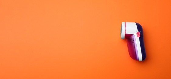 Modern fabric shaver on orange background, top view. Space for text