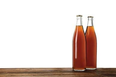 Photo of Bottles of delicious kvass on wooden table against white background