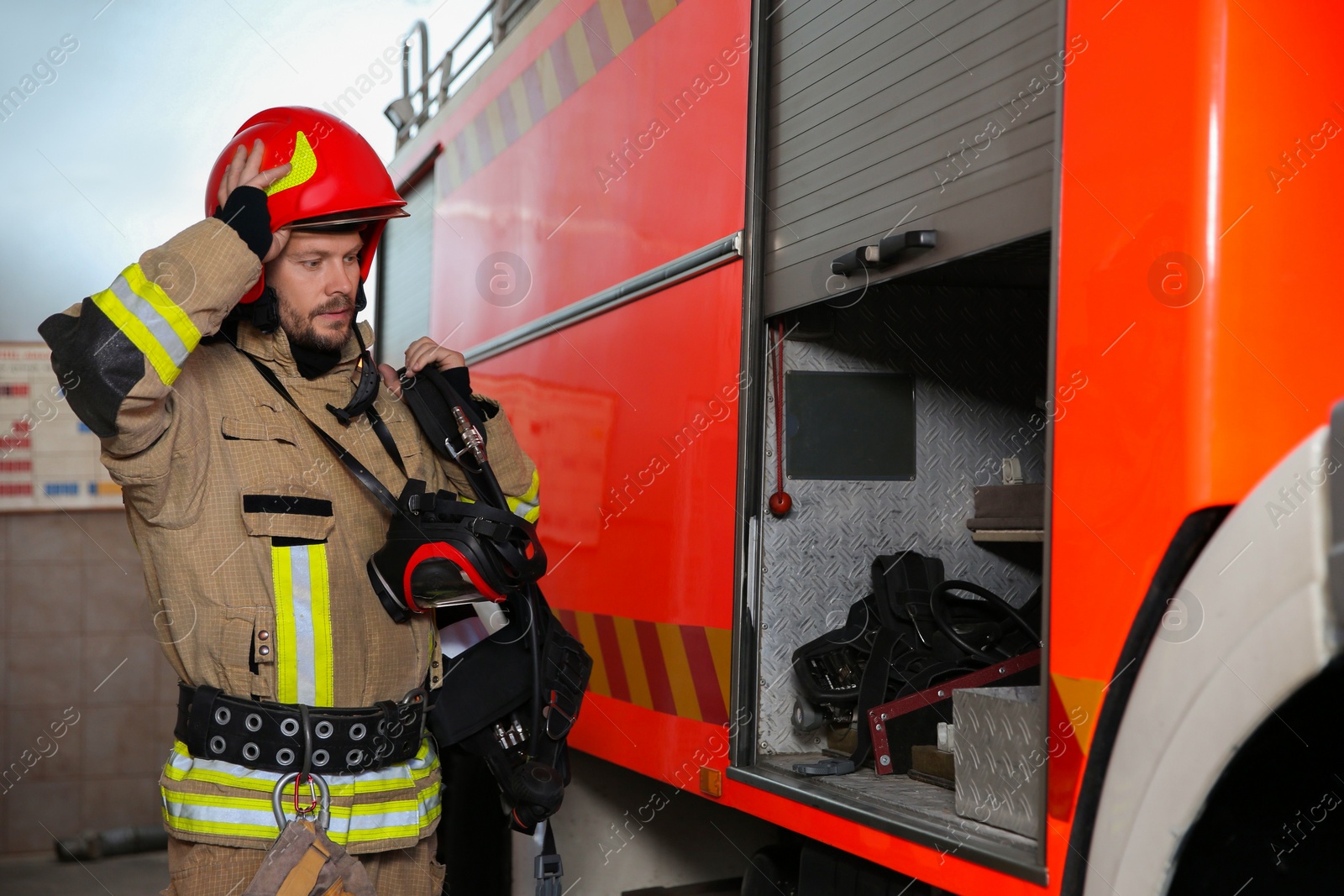 Photo of Firefighter in uniform near fire truck at station