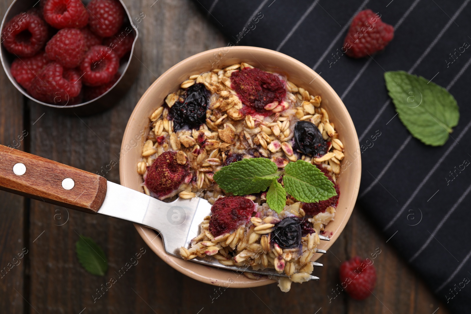 Photo of Tasty baked oatmeal with berries served on wooden table, flat lay