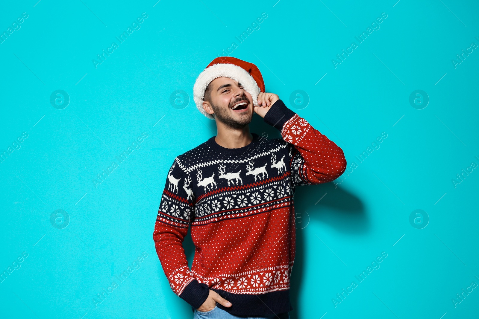 Photo of Young man in Christmas sweater and hat on color background