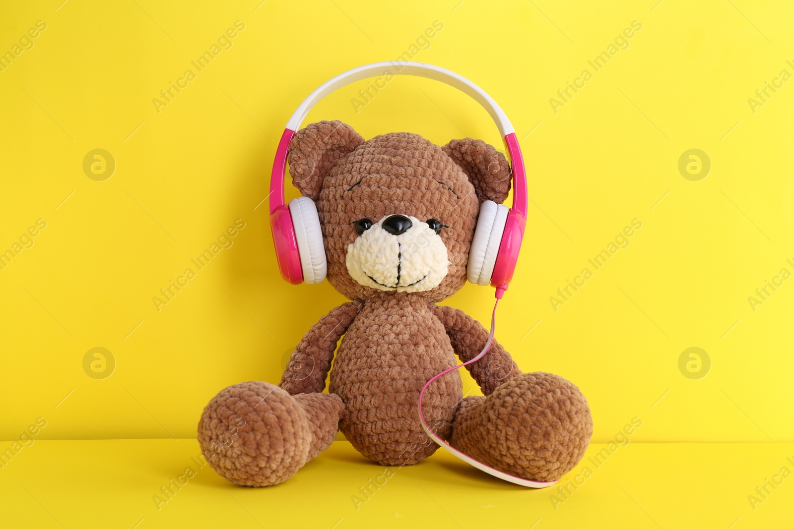 Photo of Baby songs. Toy bear in headphones on yellow background