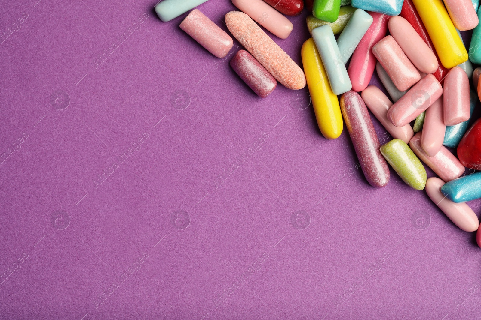 Photo of Many tasty bubble gums on purple background, flat lay. Space for text